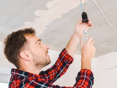 cheerful man changing light bulb at home
