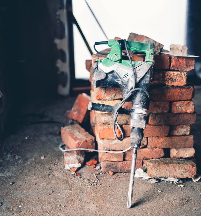Construction tool, industrial jackhammer with demolition debris and bricks