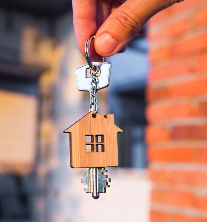 Hand with the key to the future house on the background of a construction site and walls