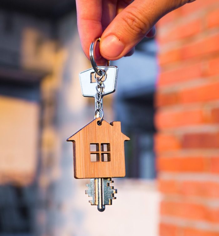 Hand with the key to the future house on the background of a construction site and walls