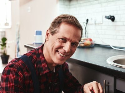 Smiling master. Seniour handyman repairing washbasin with smile