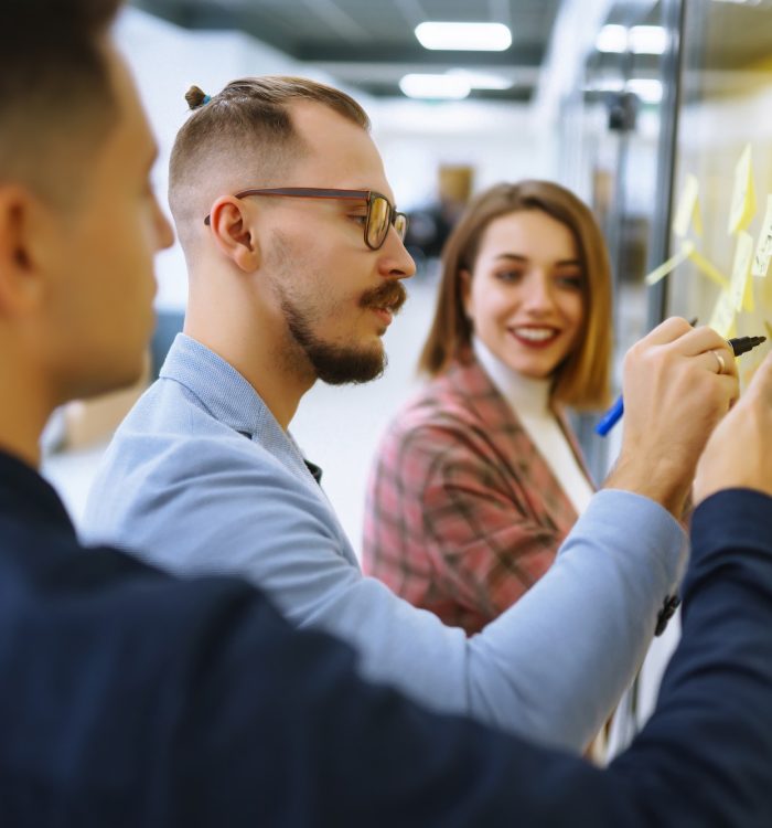 Young business people discussing and planning strategy Front of glass wall marker and stickers.